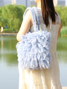 Detailed view of light blue ruffle tulle shoulder bag on white lace dress