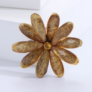 Macro detail of amber acrylic flower brooch with golden silk textures and yellow rhinestone