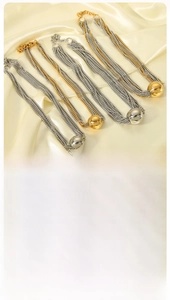Détail de colliers multicouches avec pendentifs en perles dorées et argentées sur soie