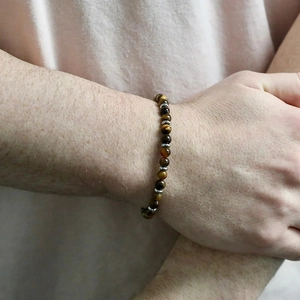 Nahaufnahme eines Tigerauge-Perlenarmbands mit silbernen Zwischenstücken am Handgelenk