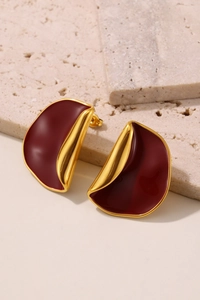 Macro detail of red enamel earrings with 18k gold plating on travertine stone