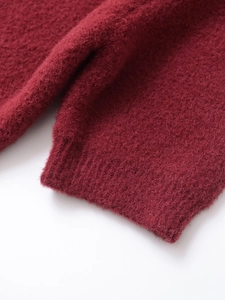 Close-up of deep red knit sweater fabric showing soft plush texture and ribbed cuff detail