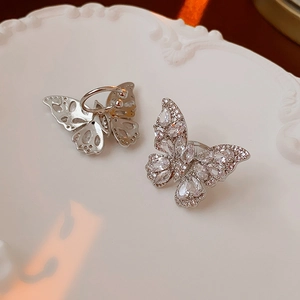 Detailed close-up of butterfly ear clips with clear zircons on a white relief plate