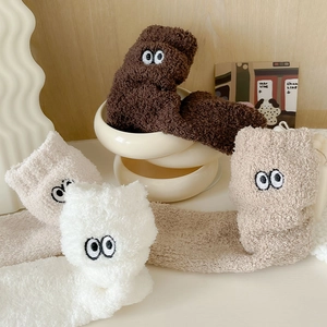 Close-up of cozy coral fleece socks with cute cartoon big eye embroidery details