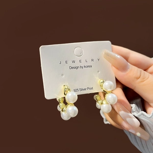 Close-up of gold pearl hoop earrings with 925 silver post shown on a jewelry card