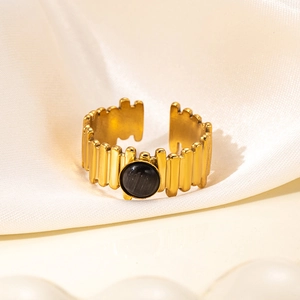 Detail of vintage 18K gold plated steel ring with black stone on beige silk fabric