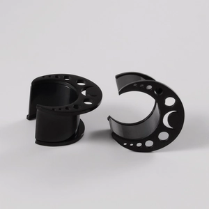 Detail view of black moon-shaped ear gauges featuring hollow dot patterns and matte finish