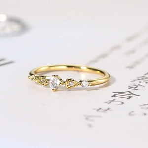 Macro shot of gold-plated ring with five-stone zircon setting and minimalist band
