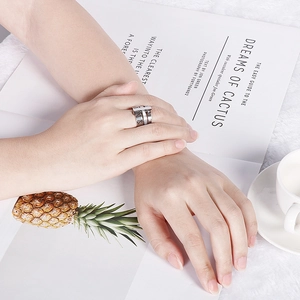 Detailed view of silver Roman numeral ring with T-bar design worn on hand near a coffee cup