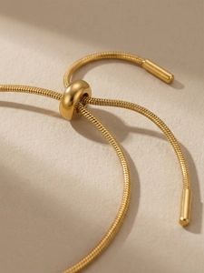 Macro detail of adjustable gold snake chain bracelet with round slide clasp and polished ends