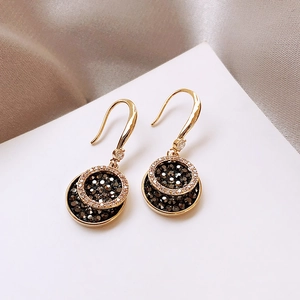 Detail of gold dangle earrings with concentric circles and black and white crystals