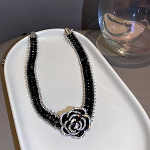 Detailed shot of a black crystal bead choker necklace with a rose pendant on white ceramic