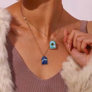 Close-up of double-layered 18K gold plated necklaces with blue enamel sun and star pendants