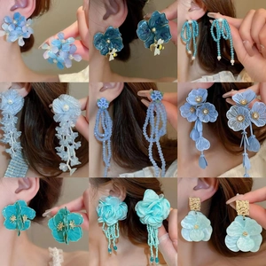 Ensemble de boucles d'oreilles papillon bleu et pétales avec perles sur un modèle