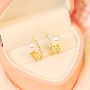 Detailed macro of elegant gold pearl drop earrings in a pink heart jewelry box