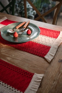 Detail of red and white woven Christmas table runner with tassels on a wood table