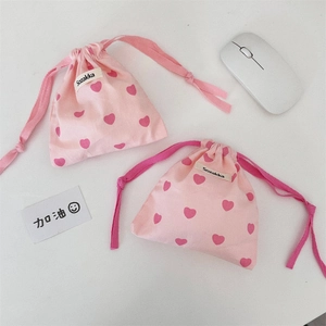 Close-up of pink heart pattern drawstring cotton tote bags with side brand labels