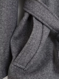 Close-up of deep grey wool coat featuring pocket stitching and waist belt detail