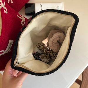 Close-up of knit cosmetic bag with red and black bow design and storage interior