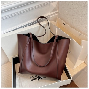 Detail of burgundy leather tote bag inside a gift box with a matching dust bag