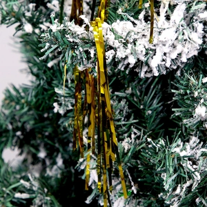 Shiny golden Christmas tinsel garland hanging on snowy pine branches for tree decoration