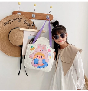 Detail of white canvas tote bag featuring cute cartoon girl print and purple straps