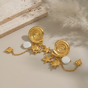 Golden sun and star tassel snail stud earrings with elegant pearls on a beige stone base