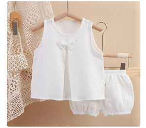 Détail d'un ensemble bébé en mousseline blanche avec tissu texturé et petit nœud
