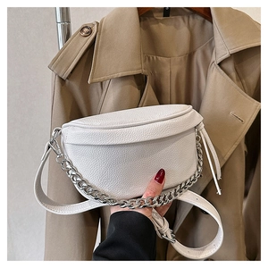 Close-up of white lychee pattern leather chest bag with silver chain on khaki coat