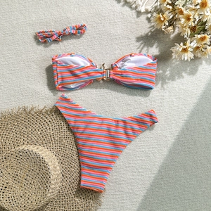 Detailed flat lay of striped bikini with metal link and matching hairband on woven mat