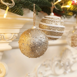 Golden 8cm Christmas ball ornaments with beads and sequins set against a fireplace
