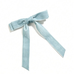 Detail of light blue velvet bow hair clip featuring long ribbons and soft fabric texture