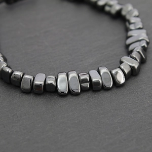 Macro shot of faceted black hematite beaded bracelet on a textured grey stone surface