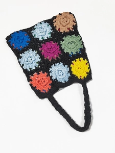 Close-up of handmade crochet bag with colorful granny square floral patterns and textures