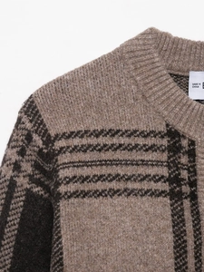 Detail of crewneck knit cardigan featuring brown checkered pattern and textured weaving