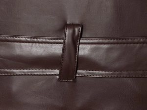 Macro shot of dark brown pebbled faux leather with vertical belt loops and fine stitching