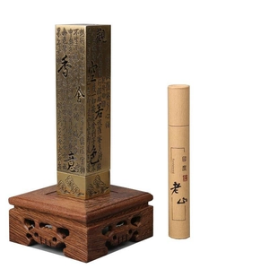 Macro shot of antique brass incense burner with heart sutra carving on sandalwood stand