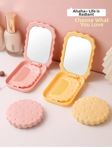 Detail of cookie-shaped portable folding makeup mirror with matching crescent comb