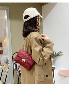 Detail of wine red quilted crossbody bag with gold geometric lock and chain strap