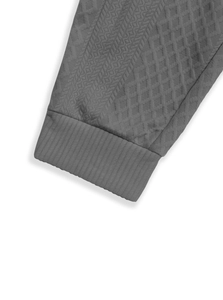 Gros plan sur le tissu en maille jacquard gris foncé et les poignets côtelés du pantalon