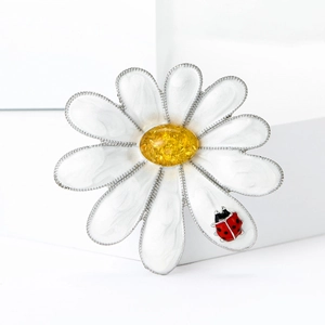 Detailed close-up of white enamel daisy brooch with yellow core and a tiny red ladybug