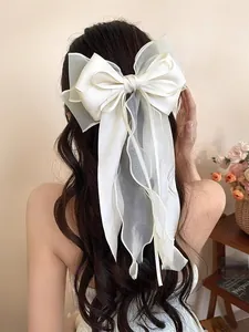 Detail of multi-layer off-white organza bow hair clip on long wavy black hair