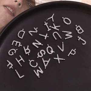 Macro view of silver stainless steel twisted letter pendants on a black tray