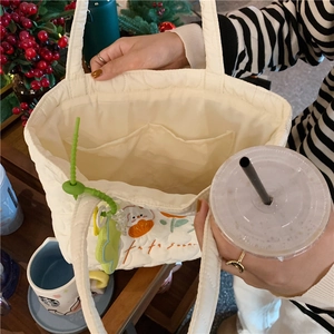 Internal detail of white quilted tote bag featuring two open pockets for organization