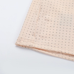 Gros plan de strass argentés étincelants sur tissu beige avec couture de bordure nette