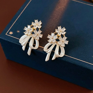 Gros plan de boucles d'oreilles nœud plaqué or avec fleurs en zircon sur écrin