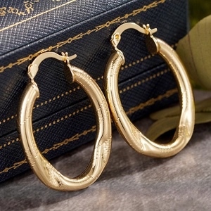 Strukturierte goldene ovale Creolen mit gebürstetem Finish auf einer Luxus-Schmuckschatulle