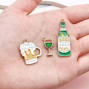 Detailed macro view of enamel beer mug and bottle charms held in hand for scale