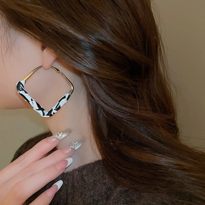 Macro view of gold square leopard print earrings worn by model with brown hair