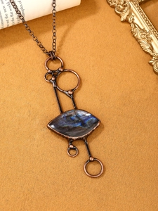 Macro view of vintage bronze pendant featuring marquise cut labradorite gemstone